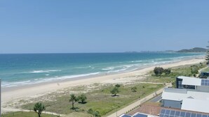 Una vista sulla costa con spiaggia, oceano e edifici sullo sfondo.