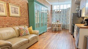A cozy living room with a leather sofa, a green cabinet, and a dining area with a table and chairs. - Charming 2 BR/2 bath in Historic District - Rent 1 Suite or Both/8-16 people! (Troy)