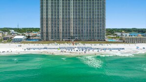 A high-rise hotel with a beach view, multiple balconies, and a swimming pool area.