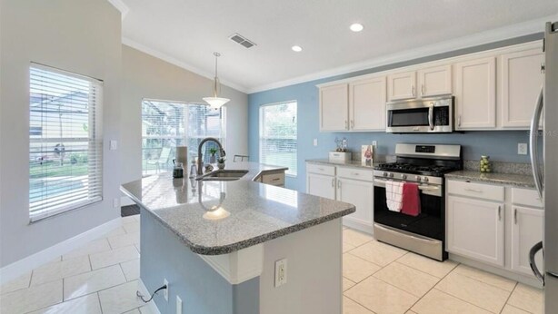 A modern kitchen with white cabinets, a granite countertop, stainless steel appliances, and a central island.