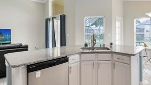 A modern kitchen with white cabinets, a granite countertop, and a built-in dishwasher.