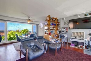 Un salon avec un canapé en cuir, une bibliothèque, un téléviseur et une grande fenêtre.