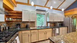 A modern kitchen with a granite countertop, stainless steel appliances, and wooden cabinetry.