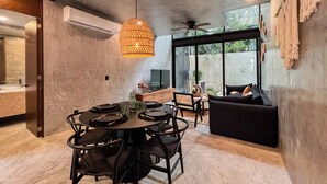 A modern dining area with a round table, black chairs, and a hanging light fixture.