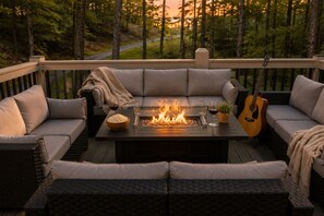 Eine Terrasse mit Feuerstelle, Sitzgelegenheiten und einer Gitarre.