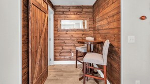 A narrow hallway with wooden walls and a small round table with two chairs. - Sand Seeker in Olivia Beach (Lincoln City)
