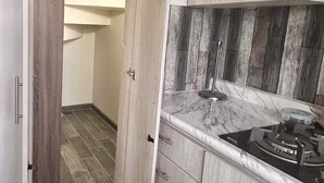 A modern kitchen with wooden cabinets, a marble countertop, and a gas stove. - Beautiful house in col independencia (Mexicali)