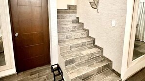 A staircase with a leaf wall art, a wooden door, and a light-colored wall. - Beautiful house in col independencia (Mexicali)