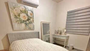 A bedroom with a bed, a dresser, a mirror, and an air conditioning unit. - Beautiful house in col independencia (Mexicali)
