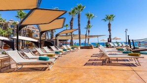 A beachside resort with rows of sun loungers, palm trees, and a clear view of the ocean. - Enjoy your Thanksgiving in the Sun and on the Beach Los Cabos (Cabo San Lucas)