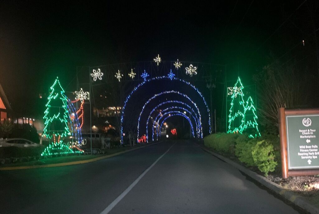 A road leading to a sign with a list of attractions including a resort, wildlife falls, fitness center, and spa.