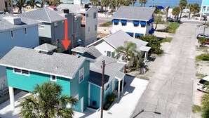 A residential area with houses along a street, a clear view of the ocean, and a prominent red arrow pointing to a house. - Charming 2-bedroom house with WiFi, AC in beautiful Treasure Island (Treasure Island)