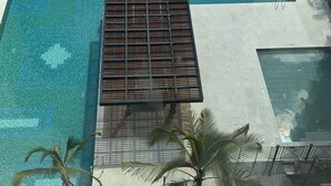 A modern pool area with clear blue water, a wooden deck, and palm trees. - Espectacular Apartament in Santa Marte (El Manantial)