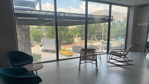 A spacious room with large windows offering a view of the outside. There are two blue chairs and a wooden rocking chair. - Espectacular Apartament in Santa Marte (El Manantial)