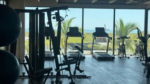 A gym with various exercise equipment, large windows, and a view of the ocean. - Espectacular Apartament in Santa Marte (El Manantial)