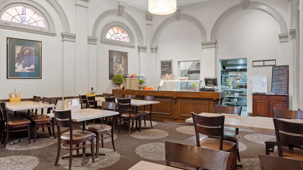 A spacious dining area with high arched ceilings, wooden tables and chairs, and a central bar area. - Euroa Hotel (Euroa)