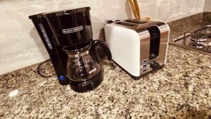 A kitchen with a coffee maker, toaster, and granite countertop.