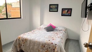 A bedroom with a bed, a window, and two framed pictures on the wall.