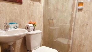 A bathroom with a sink, toilet, and shower enclosure.