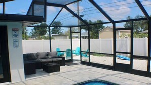 An indoor pool area with a glass enclosure, a sofa, and a pool table. - Family 2BR Heated Pool Home with Fire Pit in Seminole (Seminole)