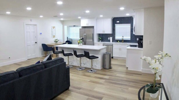 A modern kitchen with white cabinets, a central island with bar stools, and a stainless steel refrigerator. - Family 2BR Heated Pool Home with Fire Pit in Seminole (Seminole)