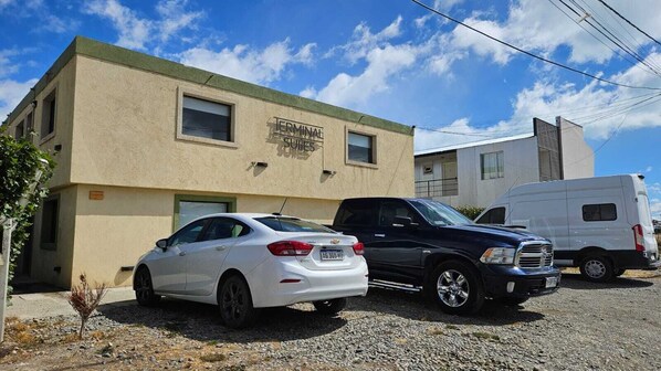 A building labeled "Terminal Suites" with a white car and a black SUV parked in front.