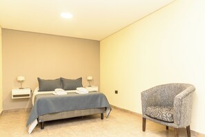 A bedroom with a bed, bedside tables, and a chair.