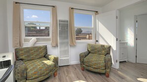 A room with two patterned armchairs, a white radiator, and a window with beige curtains.