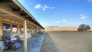 A building with a covered patio area, outdoor seating, and a view of mountains in the background.