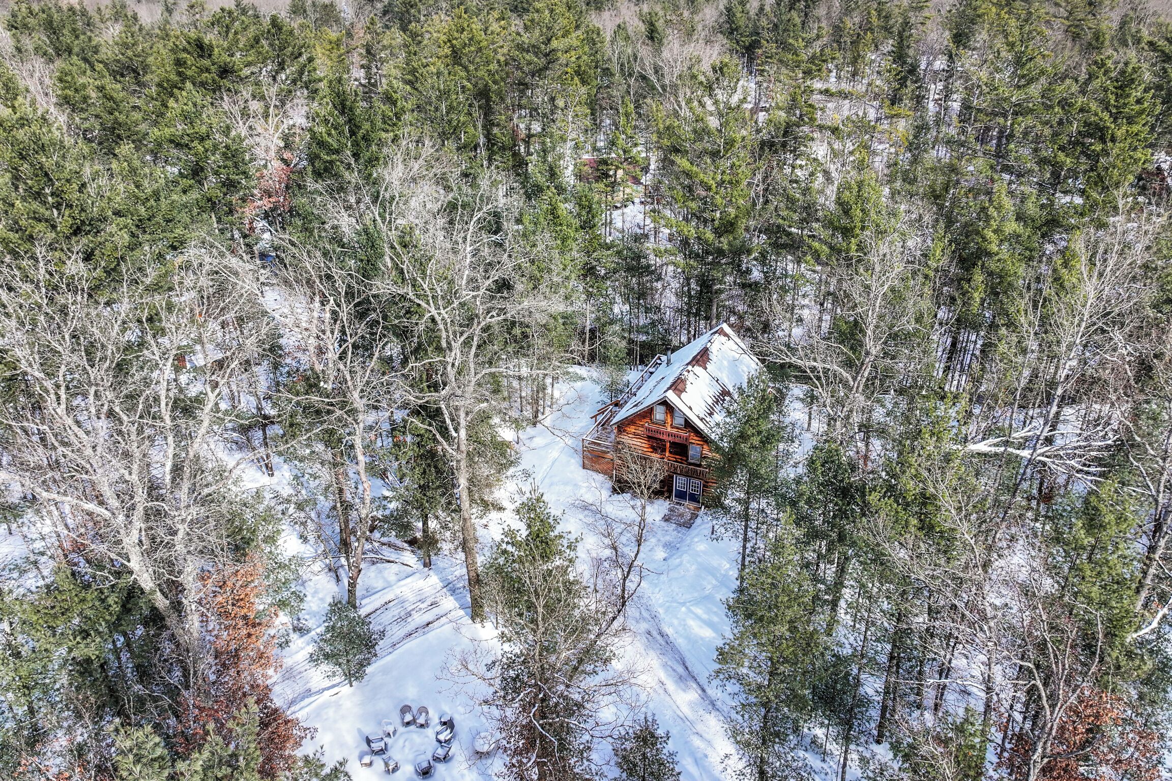A cabin surrounded by snow-covered ground and trees.