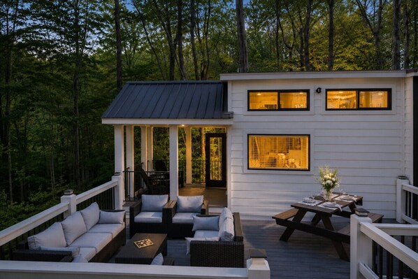 A modern cabin with a deck, outdoor seating, and a dining area.