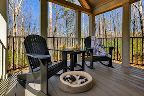 Un espace extérieur abrité, aménagé avec des chaises, une table et un panier pour chien.
