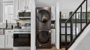 Una cocina moderna con electrodomésticos de acero inoxidable, horno empotrado y lavadora y secadora de doble puerta.