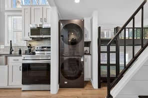 Une cuisine moderne équipée d’appareils électroménagers en acier inoxydable, d’un four encastré et d’un lave-linge et d’un sèche-linge à double porte.