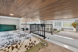 A bedroom with a bed, a window with a view, a balcony with a railing, and a ceiling with wooden panels. - Leaf Peeping Cabin | King Bed & Pets Welcome (Blairsville)