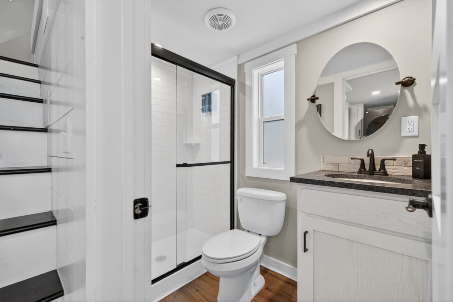 Un baño moderno con cabina de ducha de vidrio, inodoro blanco, tocador con lavabo y espejo.