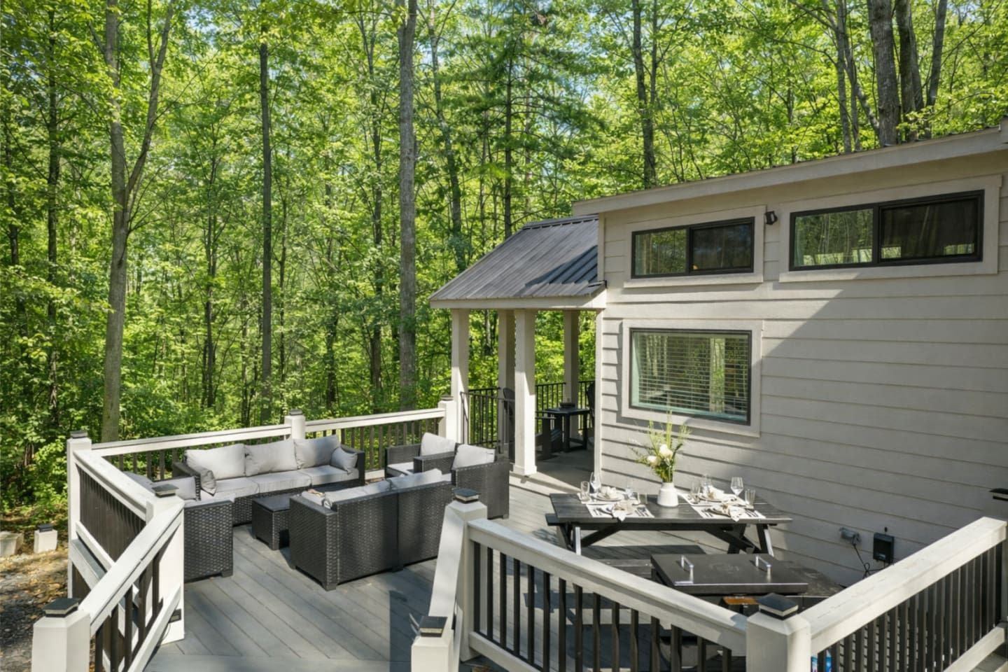 Une terrasse dotée de mobilier d’extérieur, d’un espace salon couvert et d’une table à manger pour quatre personnes.