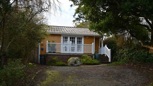 A two-story house with a front porch, a small deck, and a stone wall. - Charming 2-bedroom house in downtown Langley. (Langley)