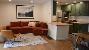 A modern living room with a sofa, a coffee table, and a rug. - Charming 2-bedroom house in downtown Langley. (Langley)
