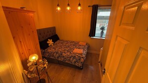 Une petite chambre à coucher, chaleureuse et accueillante, avec un lit, une table de chevet et une fenêtre avec des rideaux.