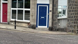 Un bâtiment en pierre avec une porte rouge, une porte bleue et une porte de garage blanche.