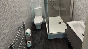 Une salle de bain moderne équipée de toilettes, d’une douche et d’une baignoire.