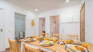 A dining area with a wooden table set for breakfast, including plates of food and orange juice. - Bright & Spacious Flat w/ Balcony by Host Wise (Portimão)