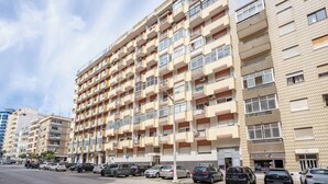 A multi-story residential building with balconies, a parking lot, and a storefront. - Bright & Spacious Flat w/ Balcony by Host Wise (Portimão)
