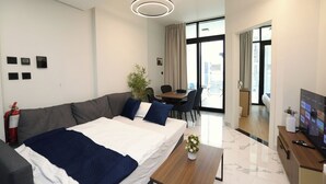 Una habitación de hotel moderna con cama, escritorio, silla, planta y televisor.