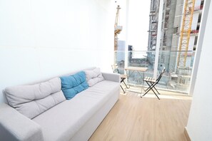 Un salon moderne avec un canapé gris, un coussin bleu et une table en verre entourée de chaises.