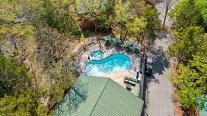 Eine Vogelperspektive zeigt ein Wohnhaus mit Swimmingpool, umgeben von Bäumen und einer Einfriedung.