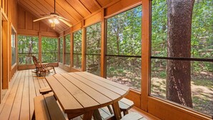 A wooden deck with a table and chairs, large windows, and a ceiling fan. - Your Branson Hideaway | 2 King Beds, Pool & Scenic Views (Branson)