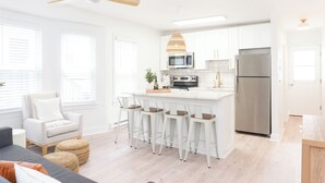 A modern kitchen with white cabinetry, a stainless steel refrigerator, a central island with bar stools, and a ceiling fan. - CrestNest- Modern 2BD, 1BA - 2.5 Blocks to Beach (Wildwood)