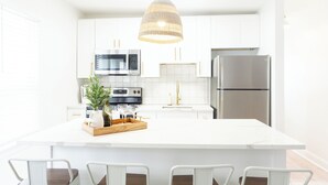 A modern kitchen with white cabinetry, stainless steel appliances, and a central island with seating. - CrestNest- Modern 2BD, 1BA - 2.5 Blocks to Beach (Wildwood)